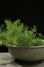 Fresh green dill in bowl on grey table, closeup