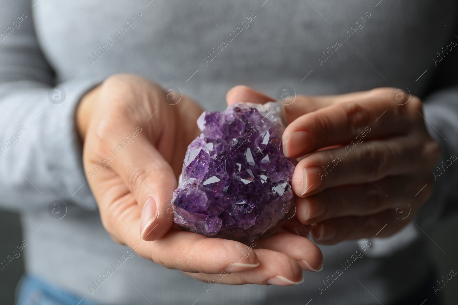 Photo of Woman holding beautiful violet amethyst gemstone, closeup