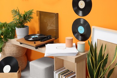 Photo of Stylish turntable with vinyl record on console table in cozy room