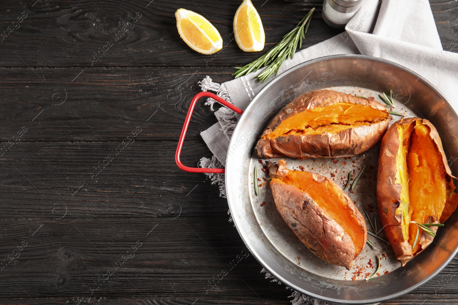 Photo of Flat lay composition with baked sweet potatoes in dish on wooden background. Space for text