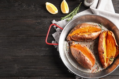 Flat lay composition with baked sweet potatoes in dish on wooden background. Space for text