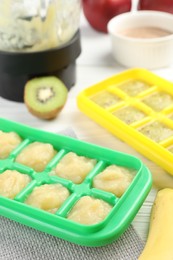 Photo of Banana and kiwi purees in ice cube tray with different fresh fruits white wooden table