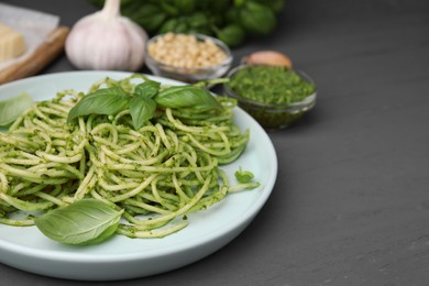 Photo of Delicious pasta with pesto sauce and basil on grey wooden table, closeup. Space for text