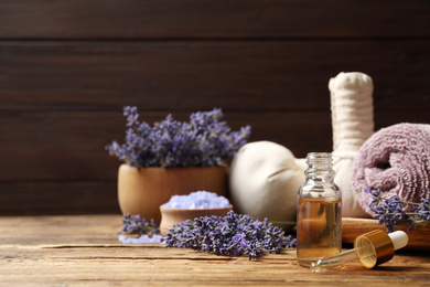 Photo of Composition with essential oil and lavender flowers on wooden table. Space for text