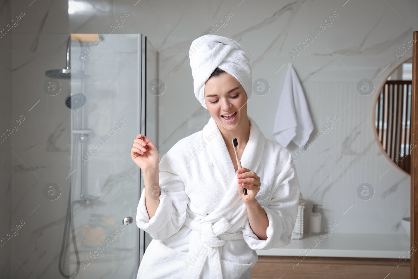 Photo of Beautiful young woman singing into toothbrush in bathroom