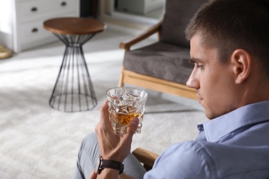 Photo of Young man with glass of whiskey at home