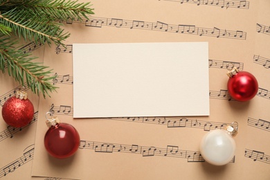 Flat lay composition with Christmas decorations and blank card on music sheets, space for text