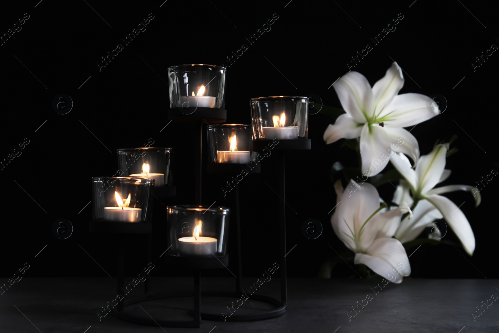 Photo of Burning candles and flowers on dark background. Funeral symbol