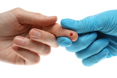 Doctor taking blood sample from patient's finger on white background, closeup