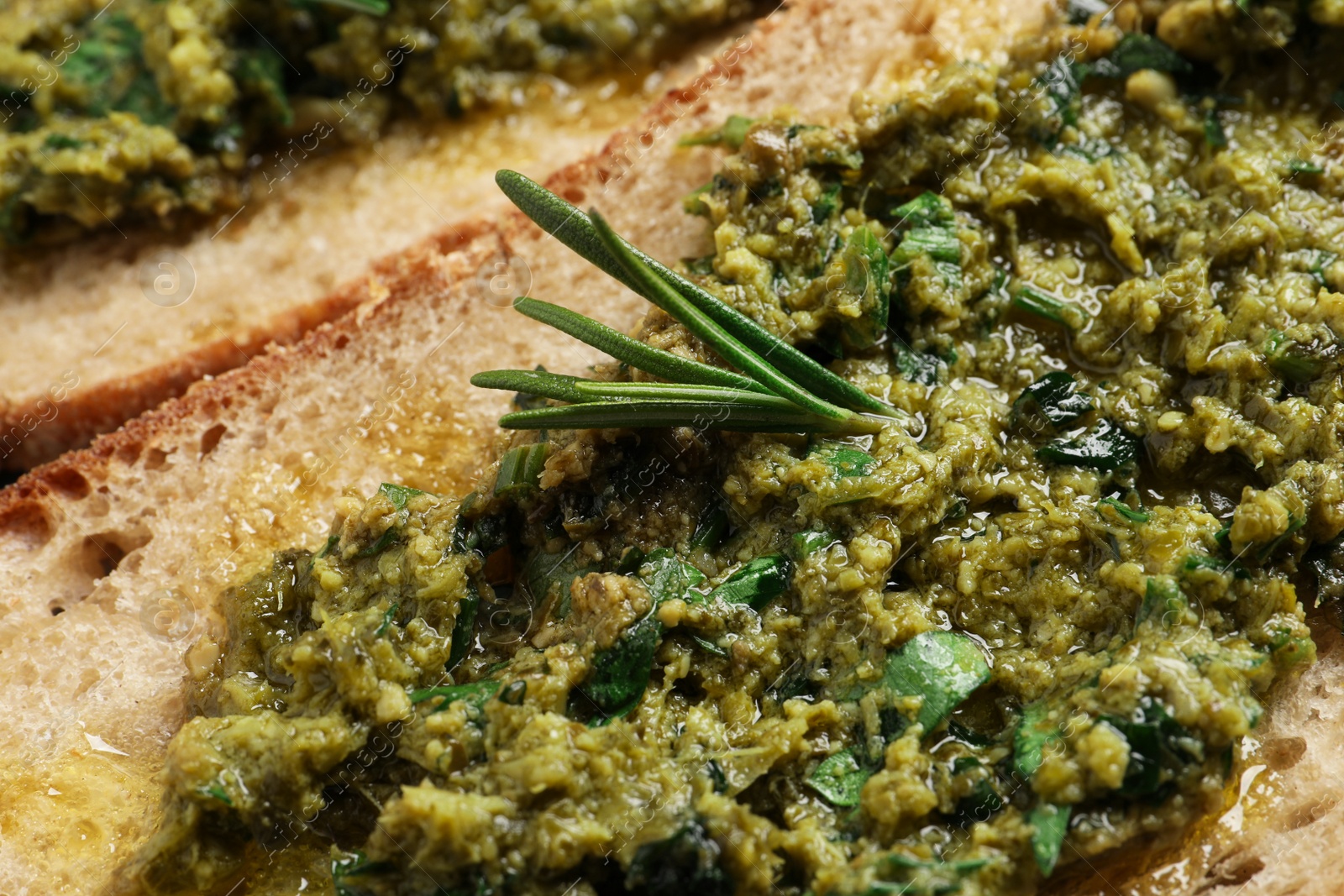 Photo of Tasty bruschetta with pesto and rosemary, closeup