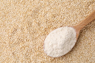 Photo of Wooden spoon with fresh quinoa flour on seeds, top view. Space for text