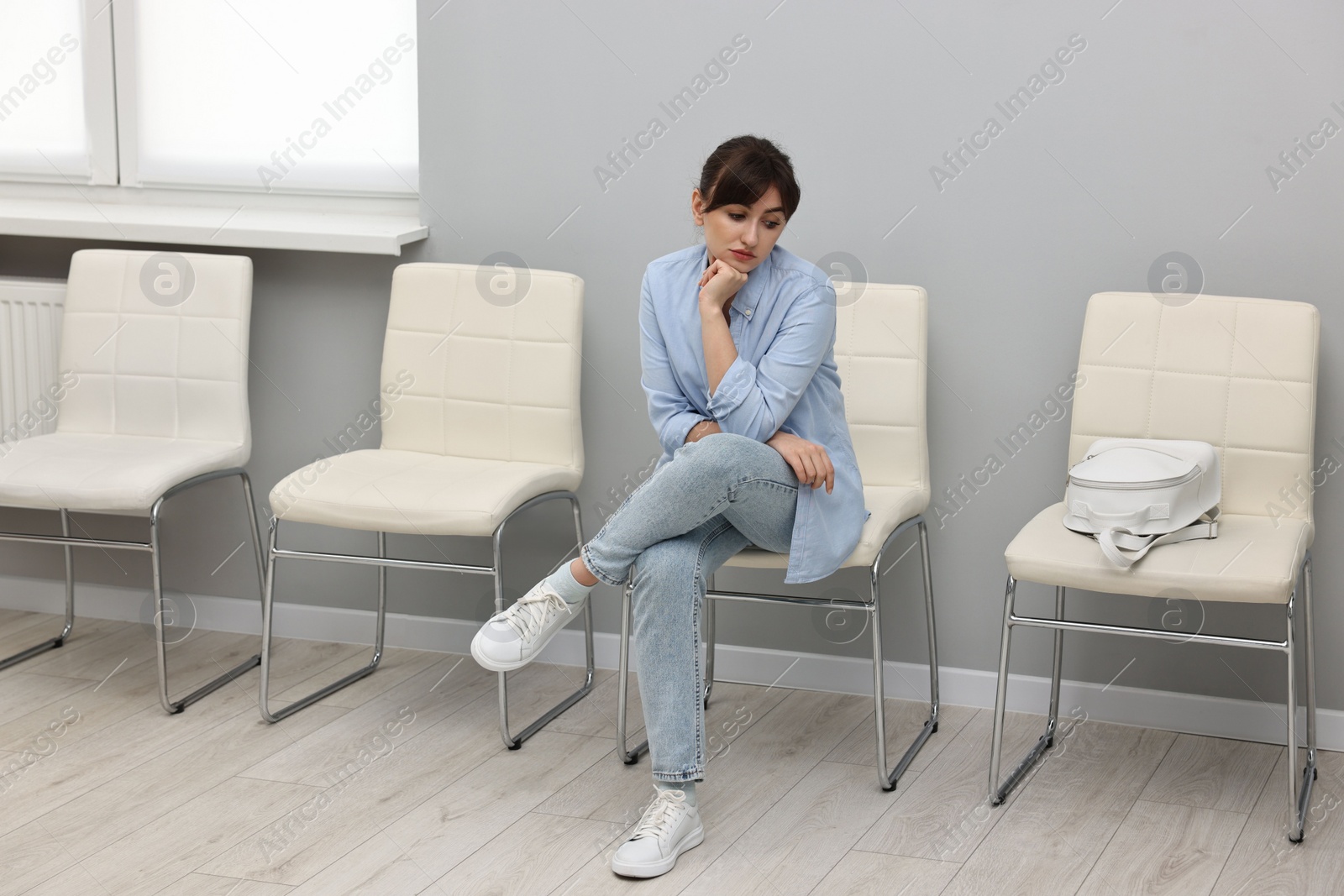 Photo of Woman sitting on chair and waiting for appointment indoors