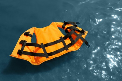 Photo of Orange life jacket floating in sea, above view. Emergency rescue equipment