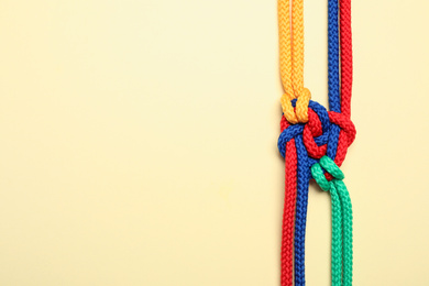 Photo of Top view of colorful ropes tied together on beige background, space for text. Unity concept