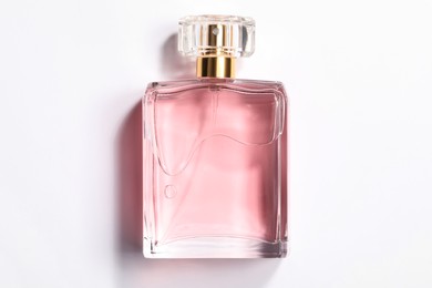 Photo of Pink women's perfume in bottle on white background, top view