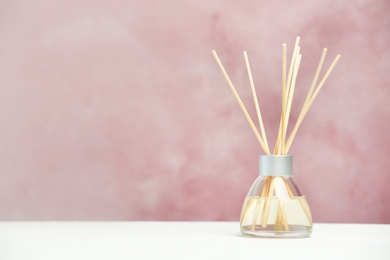 Photo of Aromatic reed freshener on table against color background