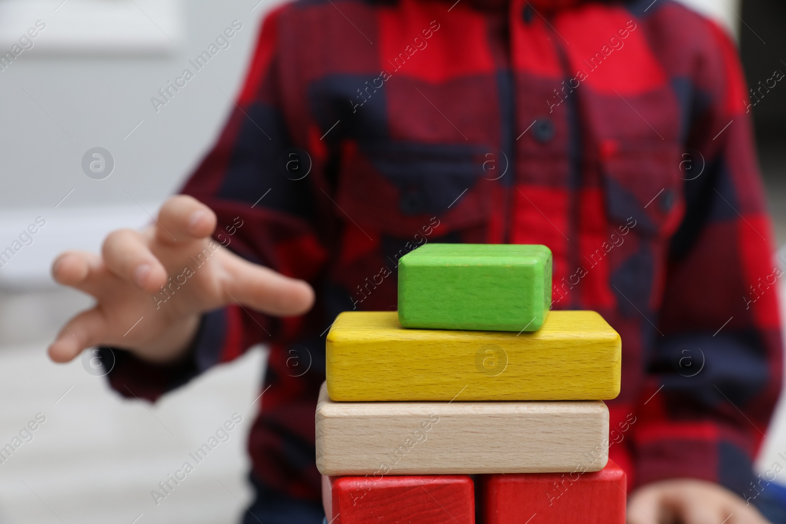 Photo of Little child playing with building blocks indoors, closeup