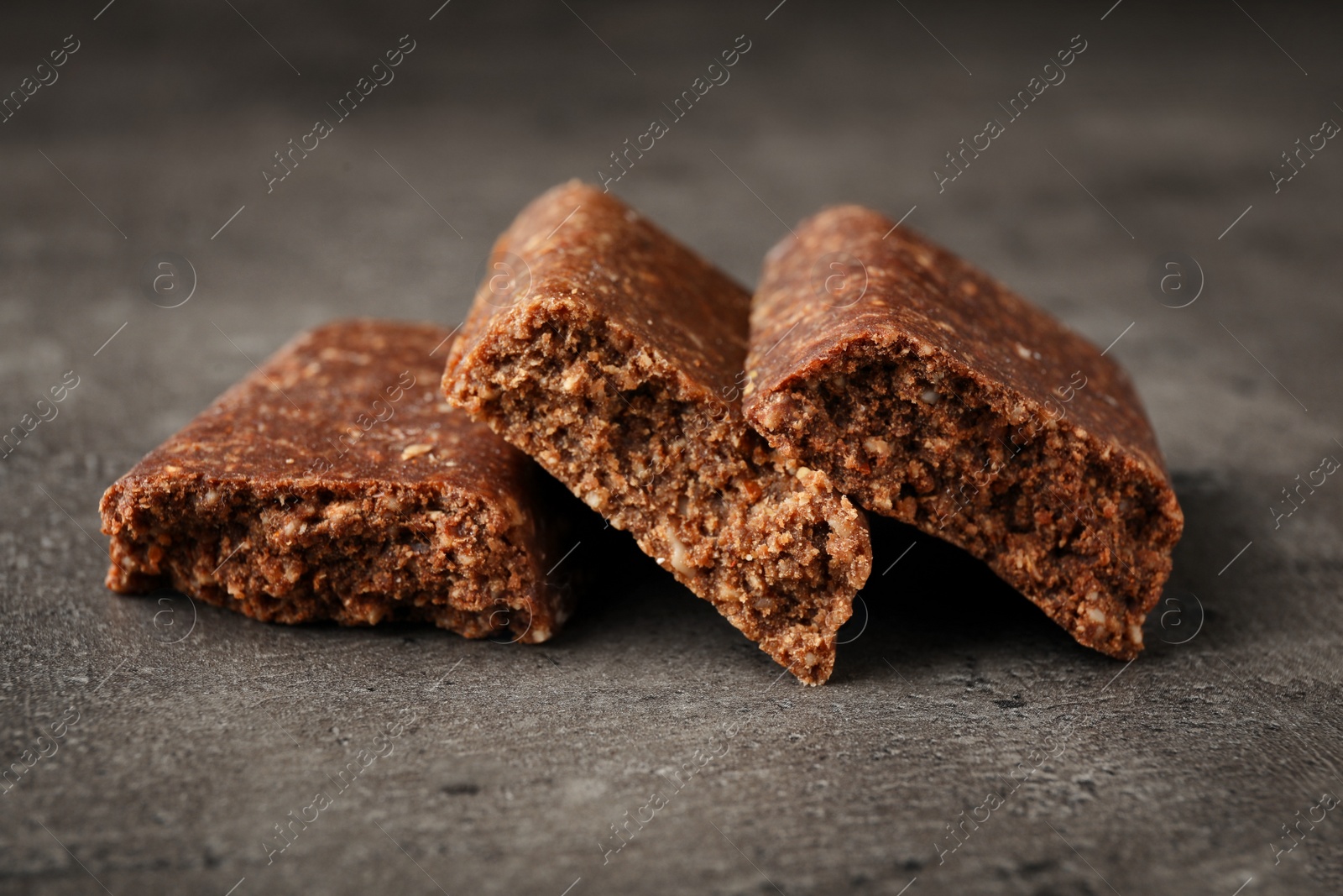 Photo of Pieces of tasty protein bar on grey table