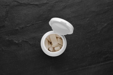 Photo of Jar with chewing gums on black table, top view