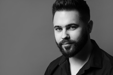 Portrait of handsome bearded man on grey background, space for text. Black and white effect