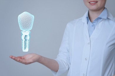 Doctor demonstrating virtual image of dental implant on light background, closeup