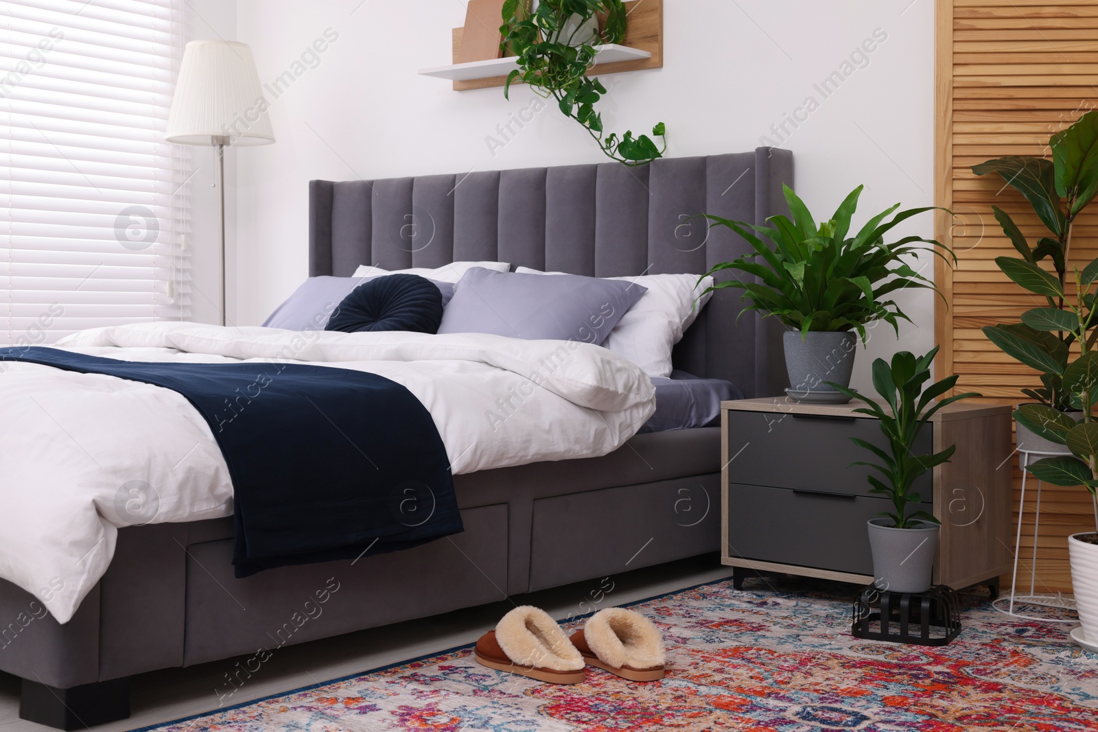 Photo of Stylish bedroom with double bed and beautiful green houseplants. Modern interior