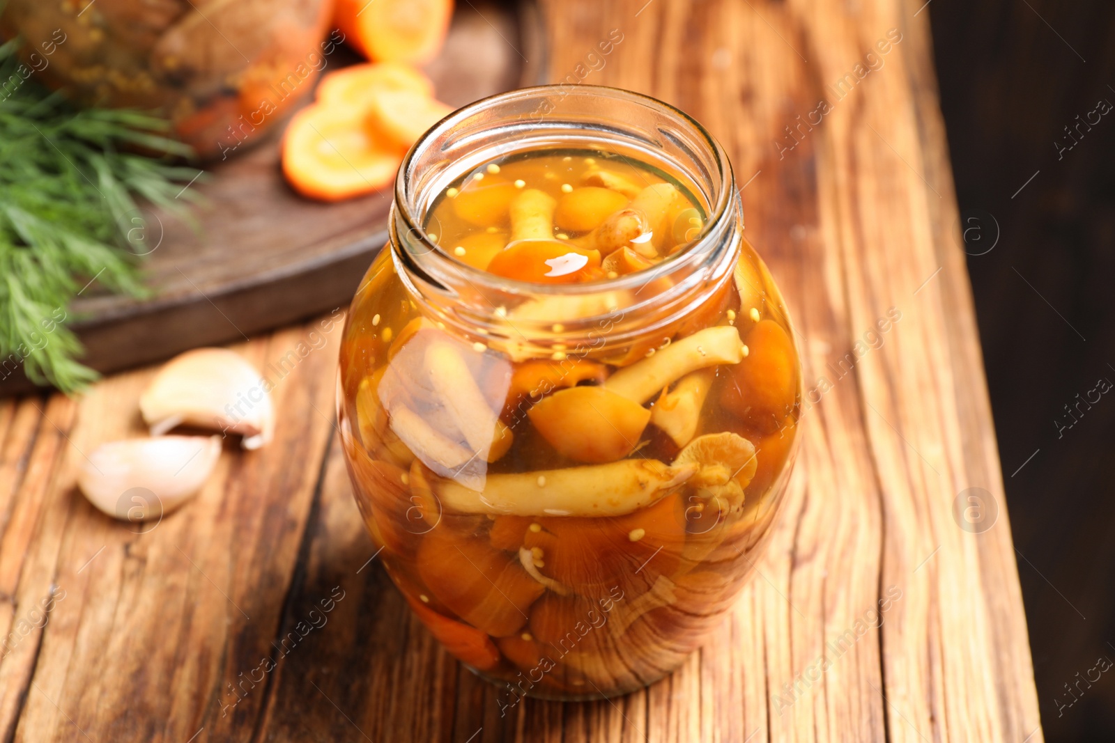 Photo of Delicious marinated mushrooms in glass jar on wooden table