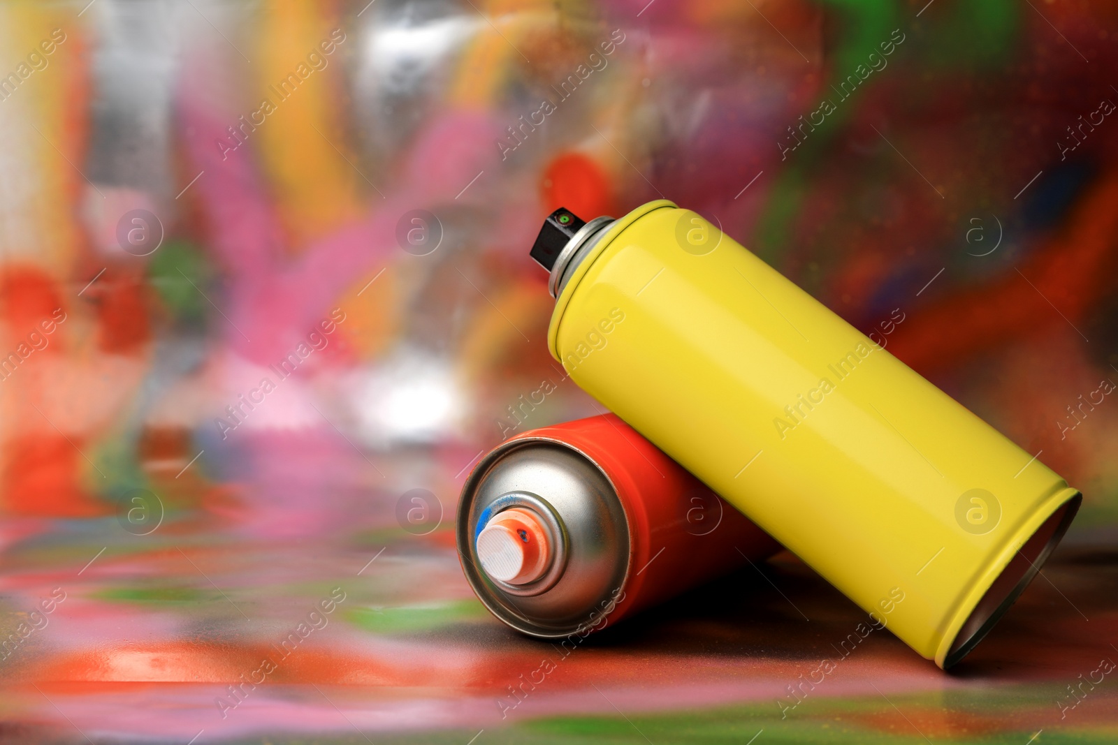 Photo of Cans of different graffiti spray paints on color background, space for text