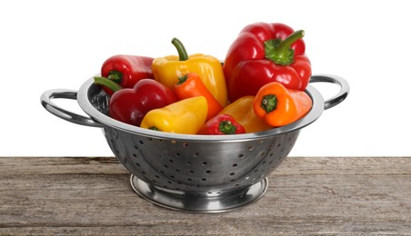 Metal colander with fresh peppers on wooden table against white background