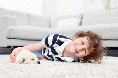Little boy with cute puppy on beige carpet indoors