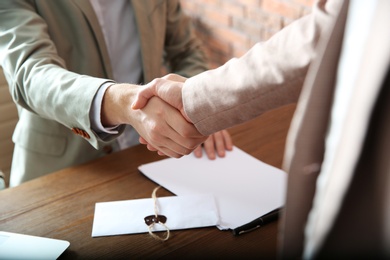 Notary and client shaking hands in office, closeup. Law and justice concept