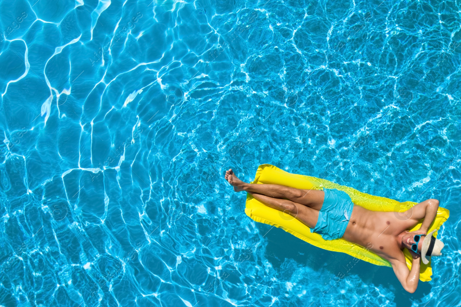 Image of Young man with inflatable mattress in swimming pool, top view. Space for text