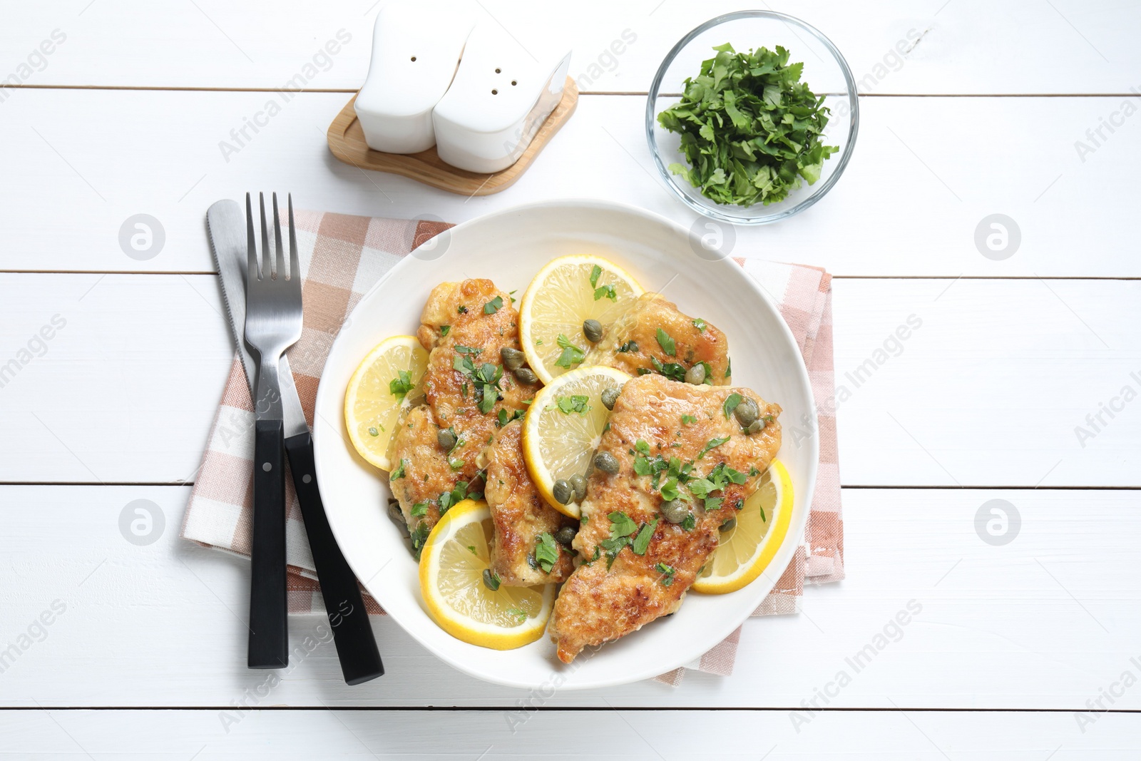 Photo of Delicious chicken piccata served on white wooden table, flat lay