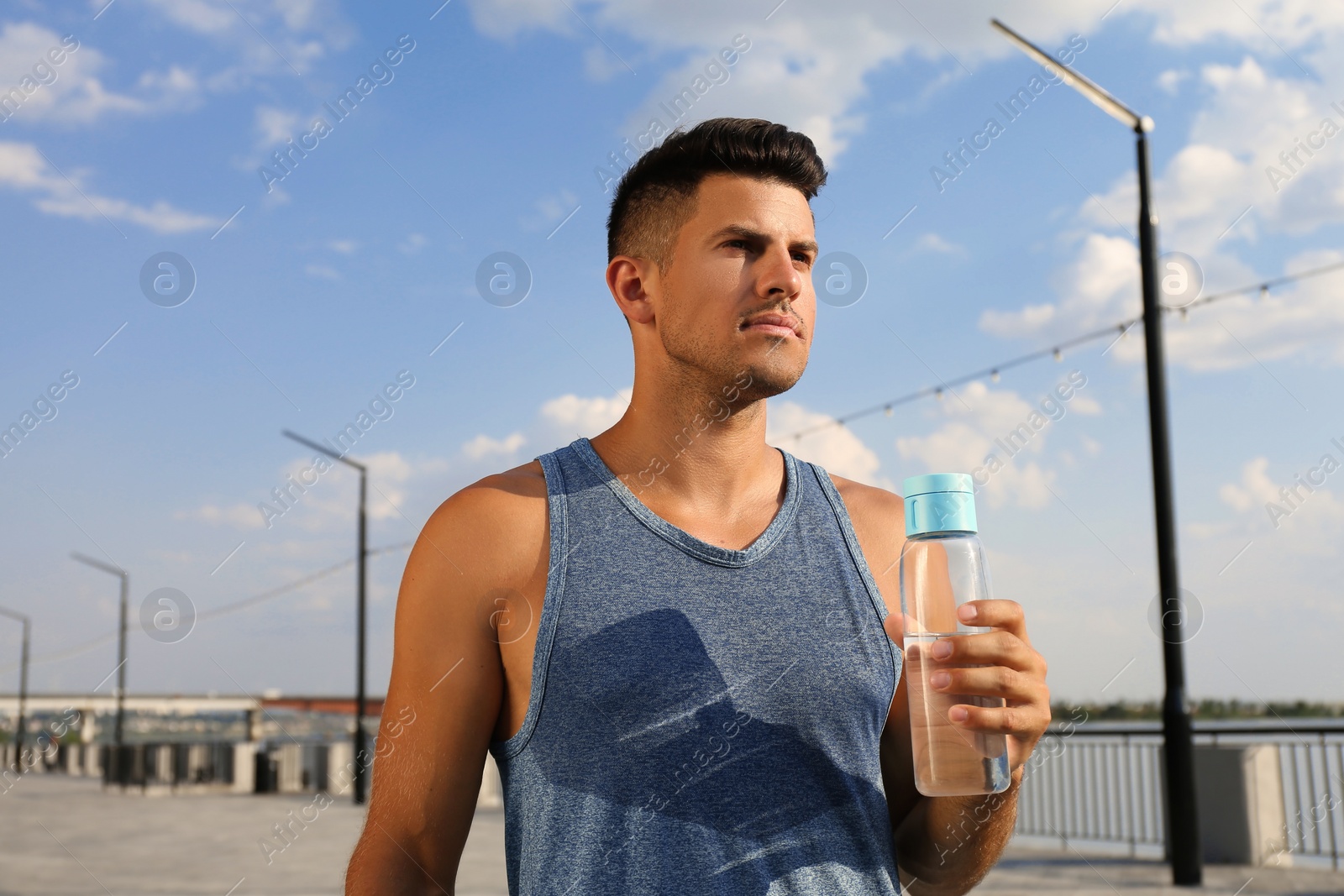 Photo of Handsome man in sportswear with bottle of water outdoors on sunny day