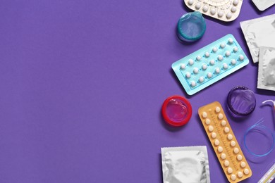 Photo of Contraceptive pills and condoms on violet background, flat lay with space for text. Different birth control methods