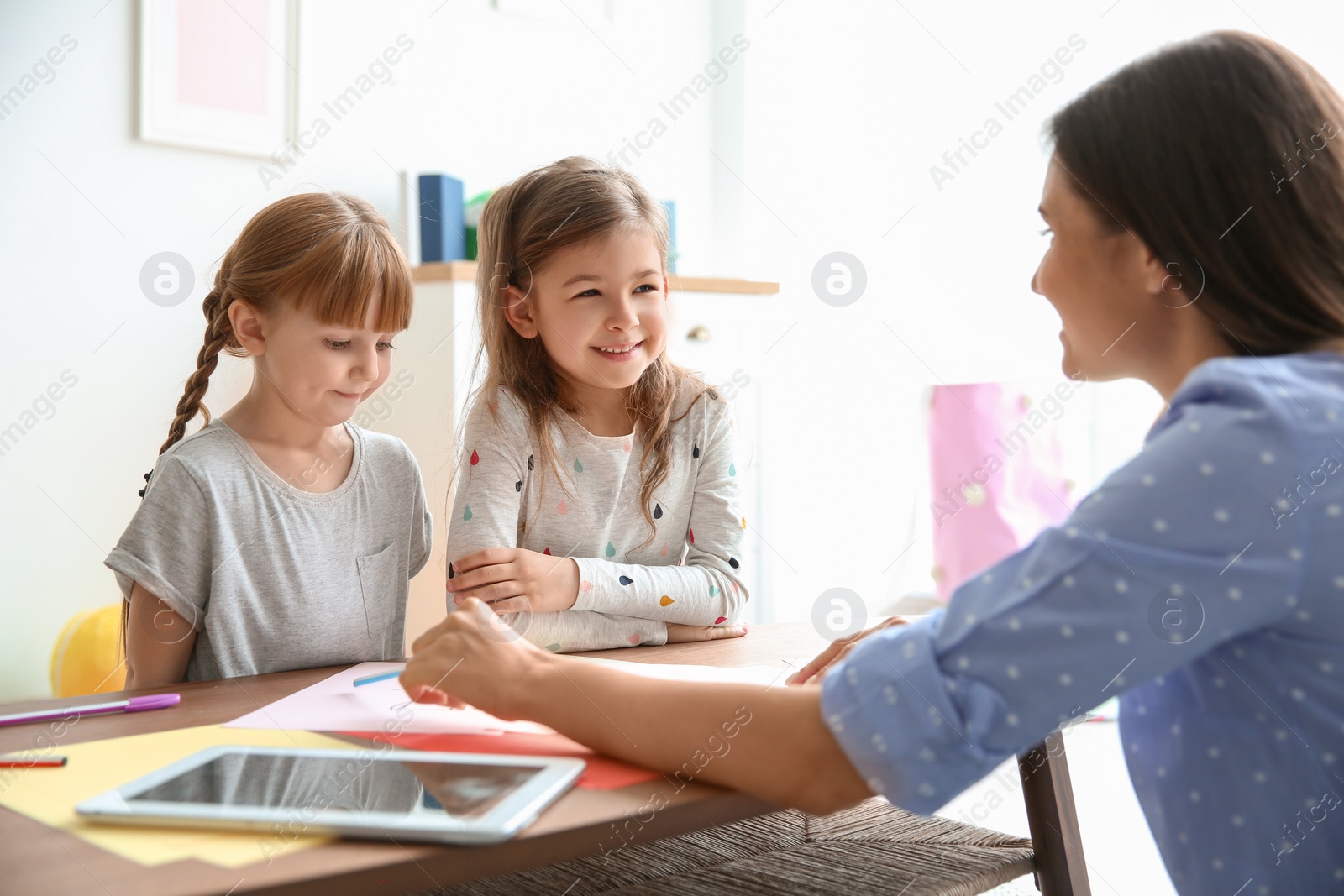 Photo of Cute little children with teacher in classroom at school