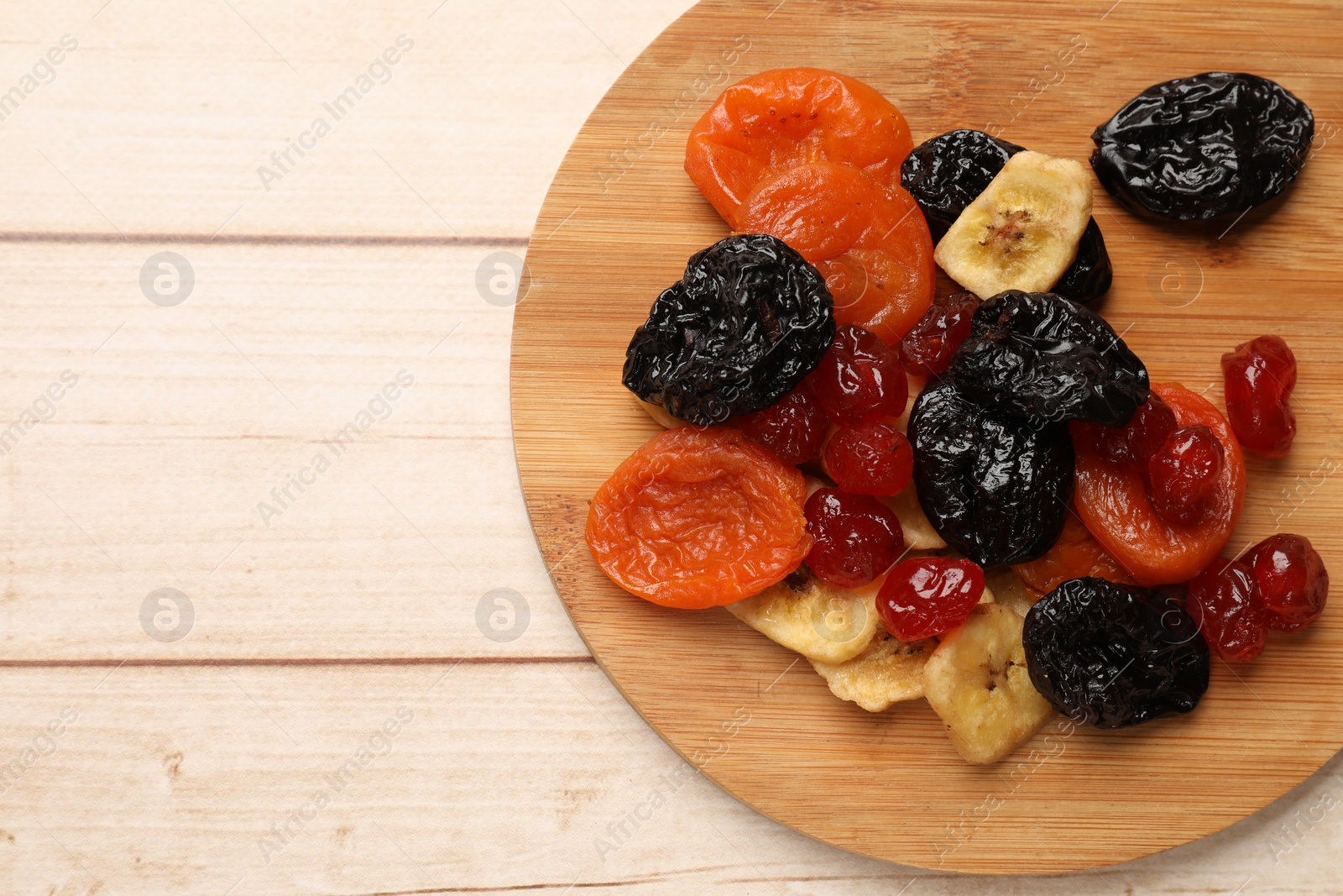 Photo of Mix of delicious dried fruits on white wooden table, top view. Space for text