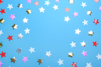 Photo of Frame of confetti stars with space for text on blue background, top view. Christmas celebration