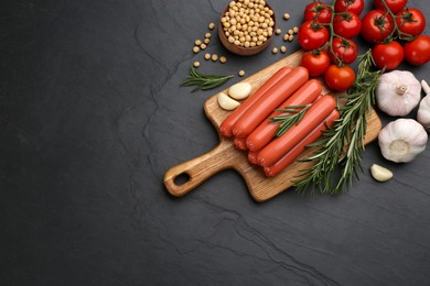 Fresh raw vegetarian sausages and vegetables on black table, flat lay. Space for text
