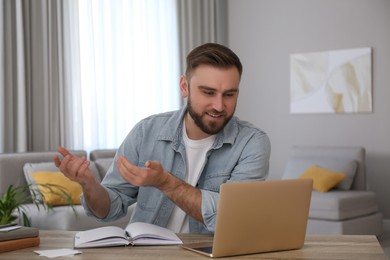 Young man watching online webinar at table indoors