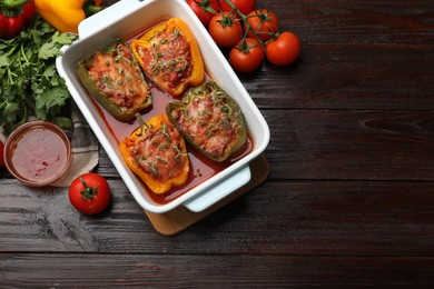 Photo of Tasty stuffed peppers in dish and ingredients on wooden table, flat lay. Space for text