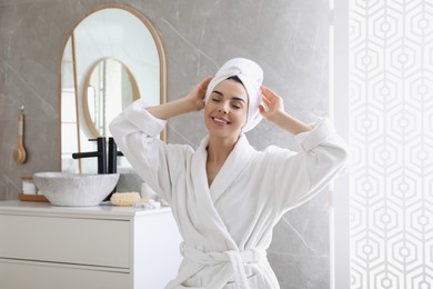 Photo of Beautiful young woman wearing soft white robe in bathroom