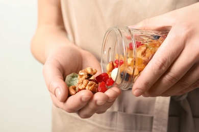 Young woman holding glass jar with different dried fruits and nuts, closeup