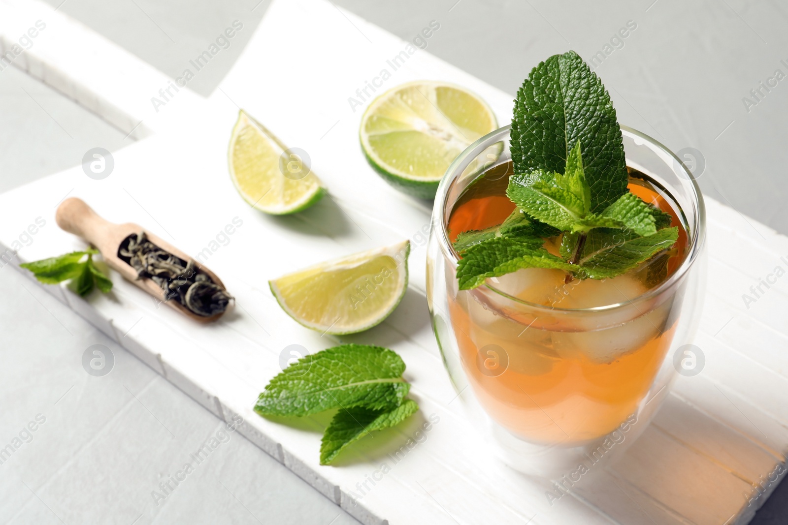 Photo of Glass with aromatic mint tea, fresh leaves and lime on wooden board