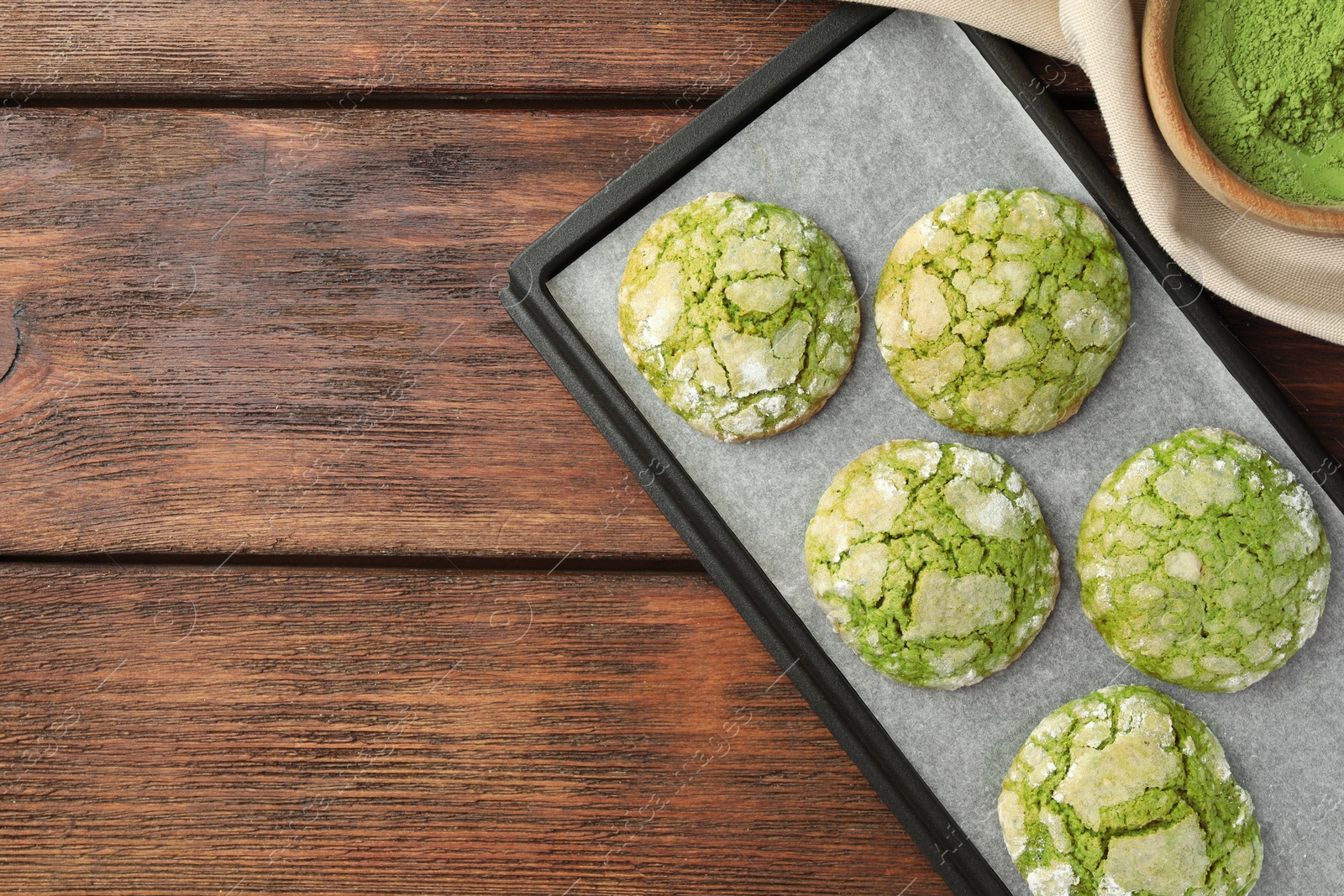 Photo of Baking tray with tasty matcha cookies and powder on wooden table, flat lay. Space for text