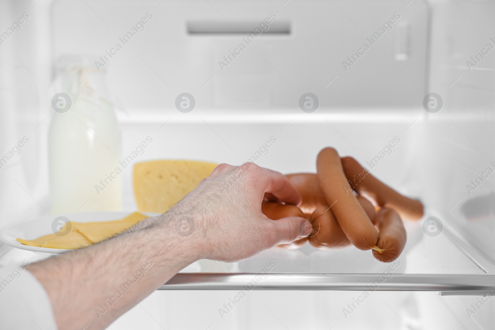 Photo of Man taking sausages out of refrigerator, closeup