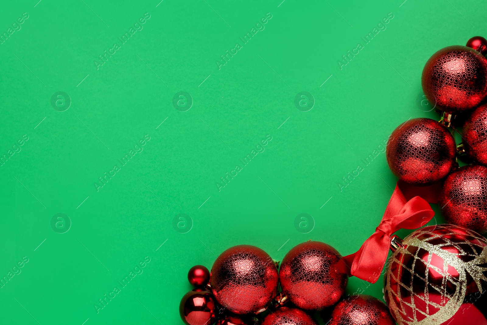 Photo of Flat lay composition with red Christmas balls on green background. Space for text
