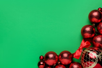 Flat lay composition with red Christmas balls on green background. Space for text