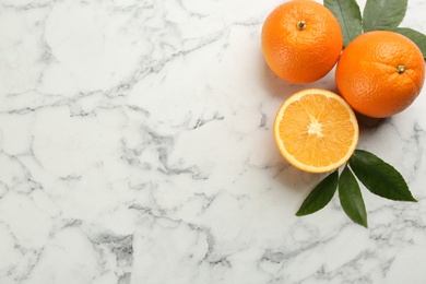 Delicious ripe oranges on white marble table, flat lay. Space for text