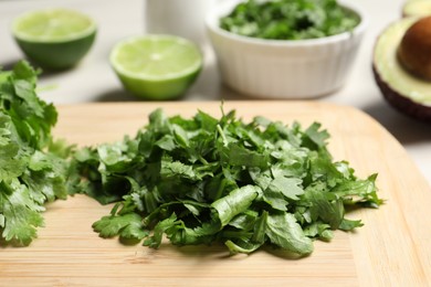 Photo of Cut fresh green cilantro on wooden board, closeup